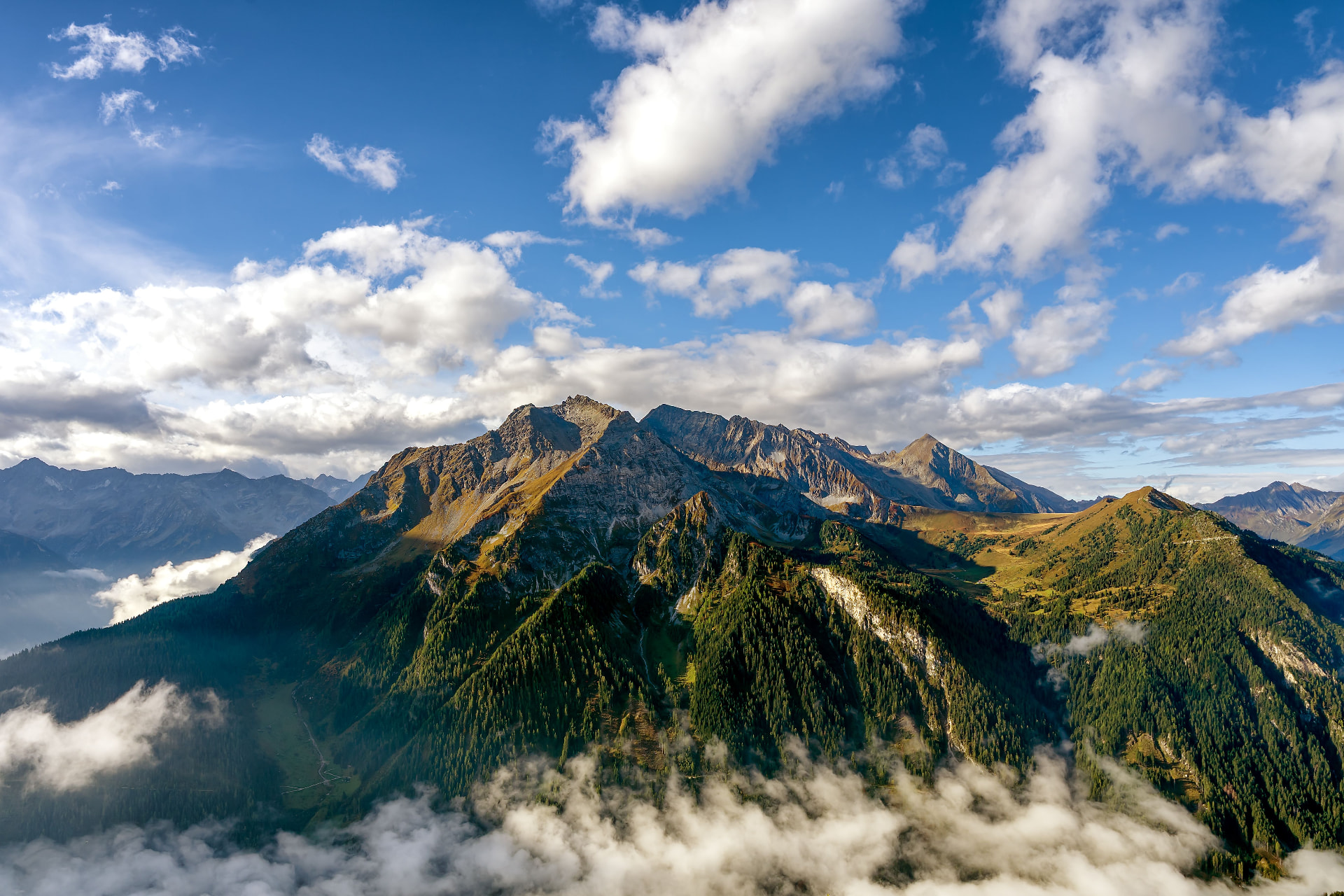 Berglandschaft mit bewaldeten Hängen und Wolken